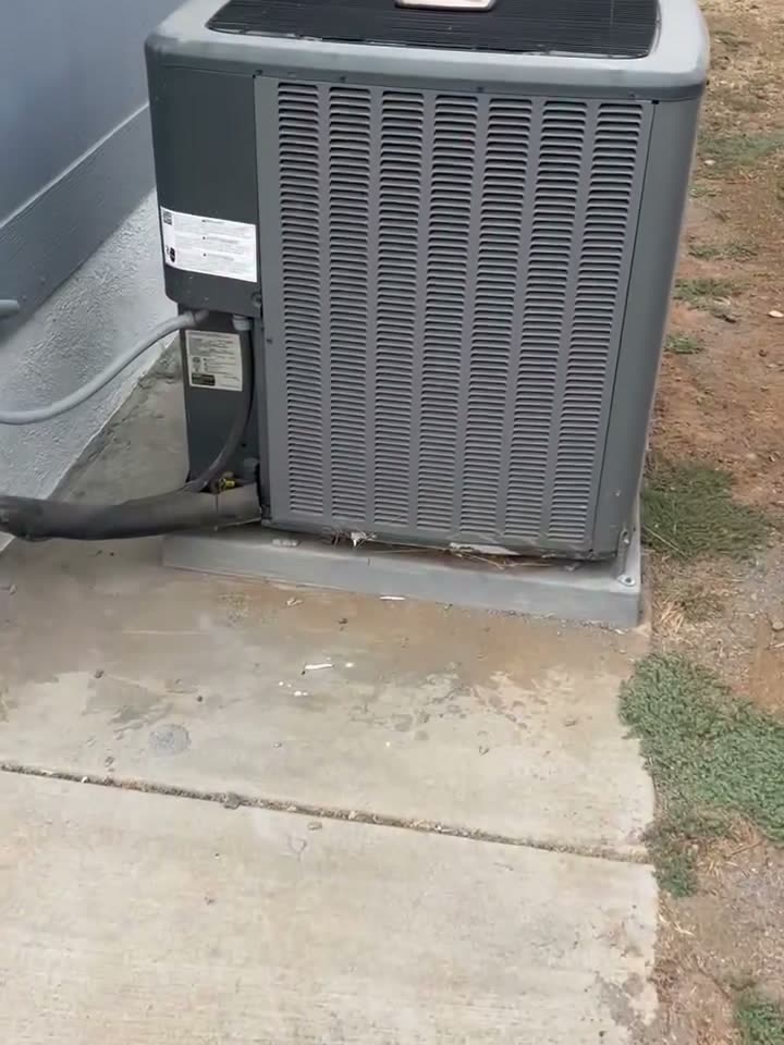 An outdoor AC condenser unit on a concrete pad beside a grey wall, the unit R&A Electric troubleshot.